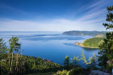 ภาพทิวทัศน์ทะเลสาบไบคาล (Baikal Lake) สีน้ำเงินเข้มจากมุมสูง มีเนินเขาปกคลุมต้นไม้สีเขียวขจีและท้องฟ้าสีฟ้าสดใส