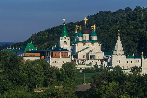 กลุ่มอาคารสีขาวหลังคาเขียวประดับโดมทองของ Pechersky Ascension Monastery ตั้งอยู่บนเนินเขาที่มีต้นไม้เขียวขจีปกคลุม
