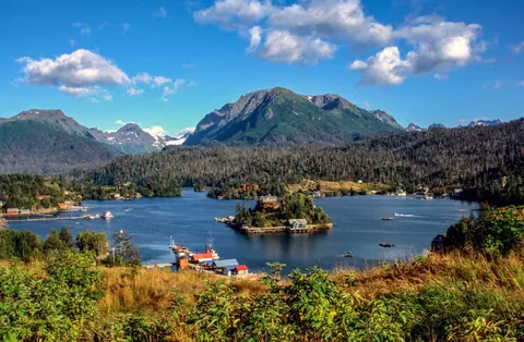 ทิวทัศน์อ่าวคาเชมัค (Kachemak Bay) แสดงผืนน้ำสีเข้มทอดตัวระหว่างแนวเขาสูงและเกาะกลางน้ำที่มีอาคารตั้งอยู่