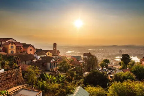 ภาพทิวทัศน์เมือง Antananarivo จากมุมสูง มีกลุ่มอาคารบ้านเรือนและหอคอยตั้งอยู่บนเนินเขาท่ามกลางแสงอาทิตย์ที่ส่องสว่าง