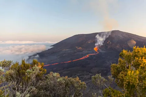 ภูเขาไฟปิตง เด ลา ฟูร์แนซ (Piton de la Fournaise) กำลังพ่นลาวาไหลลงไหล่เขาพร้อมกลุ่มควันสีขาว