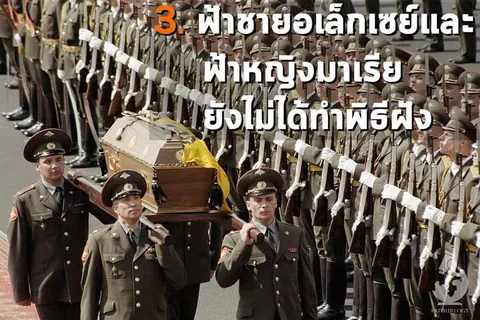 ทหารในเครื่องแบบสีเขียวหลายคนกำลังแบกโลงศพไม้สีน้ำตาลที่คลุมด้วยผ้าสีเหลือง เดินผ่านแถวทหารที่ถือปืนยาว