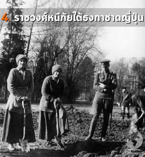 ภาพถ่ายขาวดำแสดงคนสามคนยืนบนพื้นดิน มีสองคนถือจอบปักลงดิน และอีกคนในชุดเครื่องแบบยืนกอดอกอยู่ด้านขวา