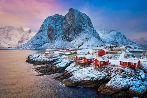 หมู่บ้านชาวประมงเกาะ Lofoten ประกอบด้วยบ้านไม้สีแดงตั้งอยู่บนโขดหินริมทะเล มีภูเขาหินสูงปกคลุมด้วยหิมะเป็นฉากหลัง