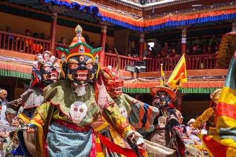 ผู้สวมหน้ากากสัตว์และชุดสีสันสดใสกำลังเต้นรำท่ามกลางผู้ชมที่ระเบียงอาคาร