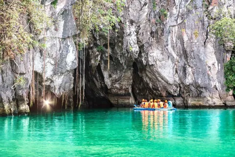 เรือยางขนาดเล็กที่มีผู้โดยสารสวมเสื้อชูชีพสีส้มลอยอยู่บนผิวน้ำสีเขียวมรกต โดยอยู่เบื้องหน้าหน้าผาหินสีเทาขนาดใหญ่ที่มีต้นไม้และเถาวัลย์ปกคลุมอยู่ด้านบน