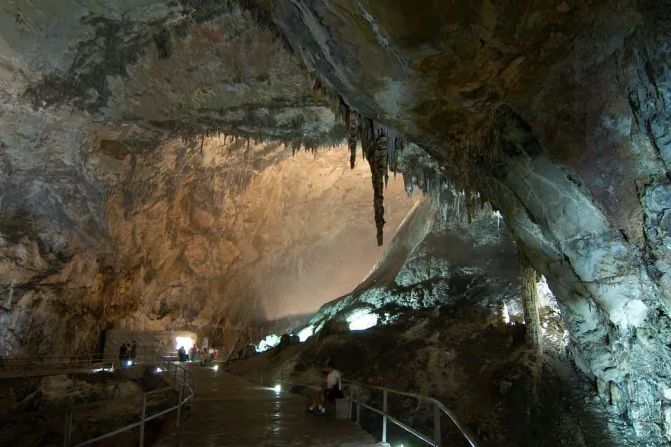 ภาพภายในถ้ำขนาดใหญ่ที่มีเพดานหินสูง มี stalactites ห้อยลงมาจากเพดาน และมีทางเดินพร้อมราวกันตกสำหรับนักท่องเที่ยว