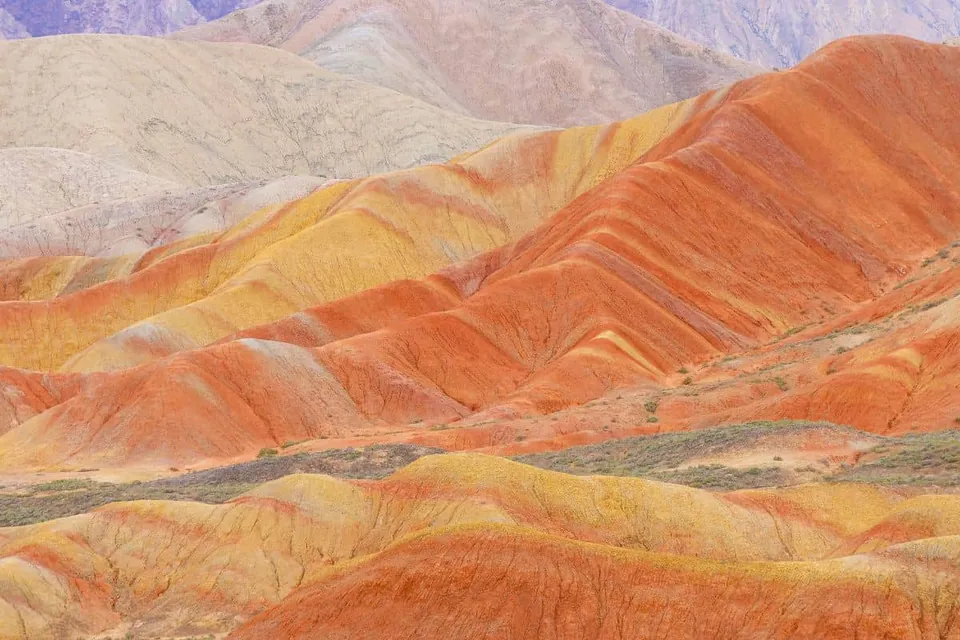 ทิวทัศน์ภูเขาที่มีชั้นหินซ้อนทับกันเป็นชั้นๆ ในเฉดสีส้ม แดง เหลือง และครีม