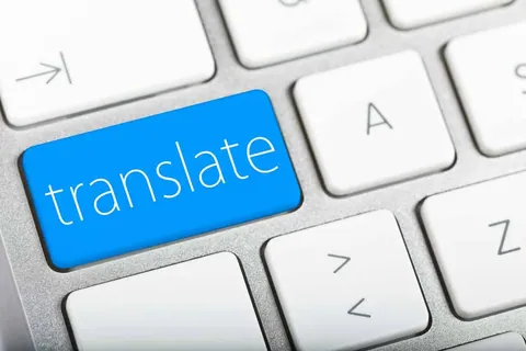 ภาพใกล้ปุ่มคีย์บอร์ดสีน้ำเงินที่มีตัวอักษรภาษาอังกฤษว่า translate อยู่ท่ามกลางปุ่มคีย์บอร์ดสีขาว