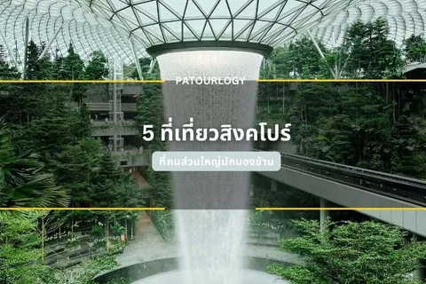 น้ำตกขนาดใหญ่ไหลลงจากเพดานโครงเหล็กแก้วกลางสวนป่า มีข้อความ "PATOURLOGY" และ "5 ที่เที่ยวสิงคโปร์" ปรากฏบนภาพ