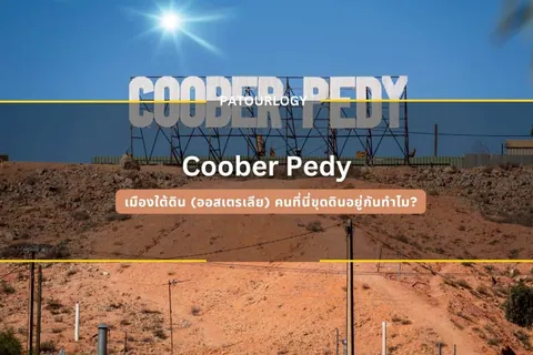 ป้ายโครงเหล็กขนาดใหญ่เขียนว่า COOBER PEDY ตั้งอยู่บนเนินดินสีส้ม มีดวงอาทิตย์ส่องสว่างบนท้องฟ้าสีน้ำเงิน และมีข้อความไทยทับอยู่ด้านล่าง