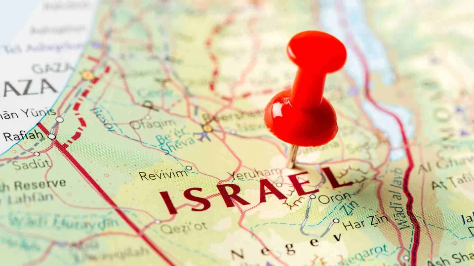 หมุดสีแดงปักอยู่บนแผนที่ที่มีตัวอักษรภาษาอังกฤษ 'ISRAEL' พิมพ์ด้วยสีแดงขนาดใหญ่