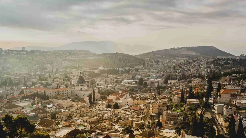 ภาพมุมกว้างของเมือง Nazareth ที่เต็มไปด้วยอาคารบ้านเรือนและเนินเขาในพื้นหลัง